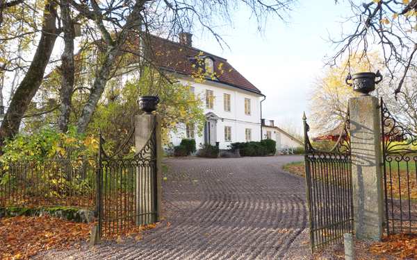 Entré på Spellinge herrgård med grindar till ett stort vitt hus.