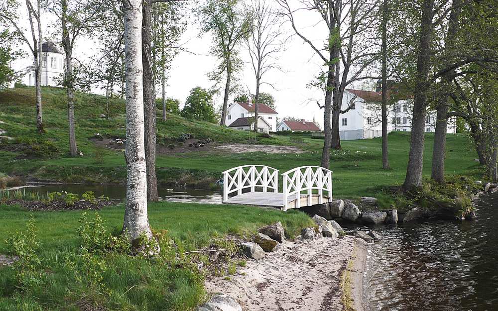 Trädgård med grönska på Stjärnvik säteri och en vit bro.