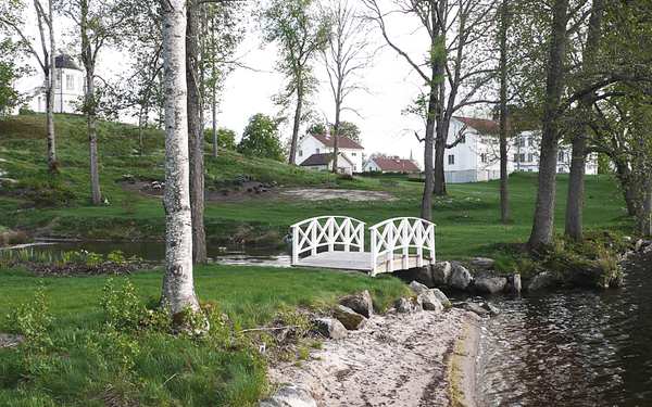 Vit bro i grön trädgård vid Stjärnvik säteri.