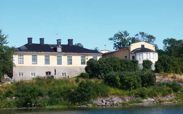 Stora stenhus bakom grönska och vatten på Thorönsborgs herrgård.