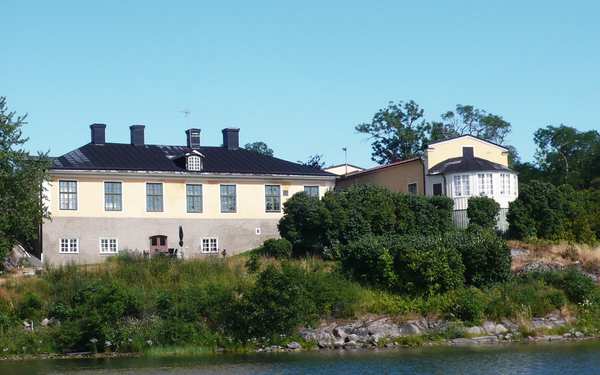 Stora stenhus bakom grönska och vatten på Thorönsborgs herrgård.
