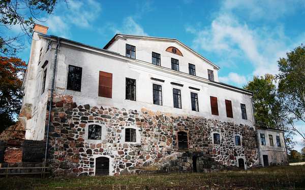 Vitt hus med stenar som grund på Vinäs slottsruin.