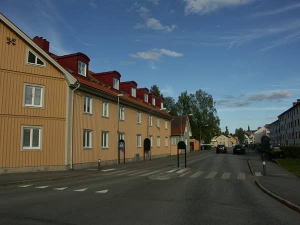 En väg med trähus, gula och turkosa, vid Gamla Brandstationen.