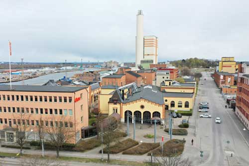 Flera byggnader i ett industriområde på Triangeln Södra Hamnen i Norrköping med fokus på en gul stadsbyggnad.