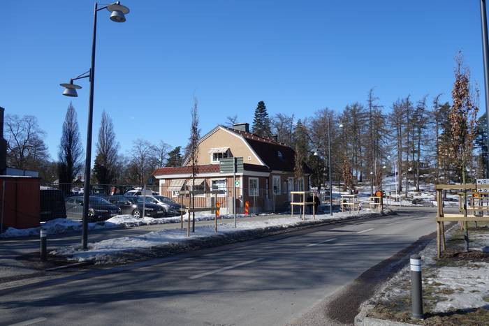 Bilväg där det skymtas en byggnad och parkering i bakgrunden vid Universitetssjukhuset i Linköping.